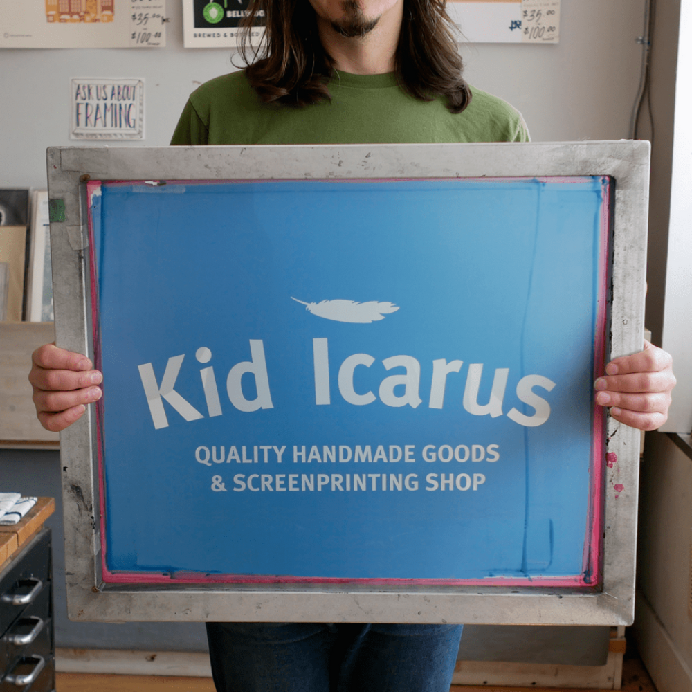 A person holding a screen print that reads