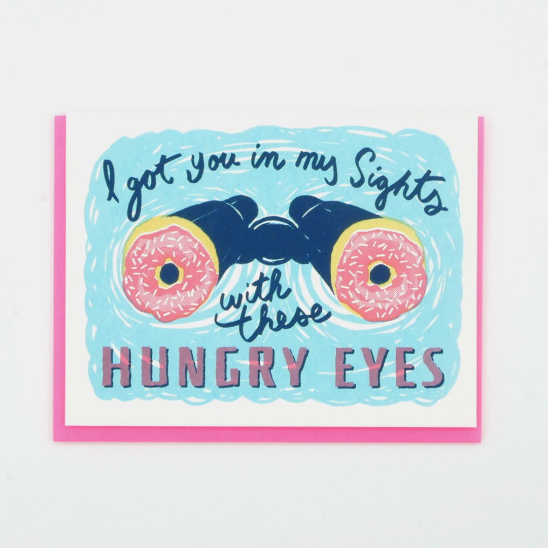 Hungry Eyes Love Card: A greeting card with an image of binoculars with donuts for eyes and the words "I got you in my sights with these HUNGRY EYES"