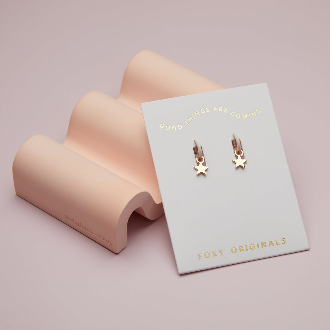 Gold star earrings on a 'Foxy Originals' branded card with a pink background