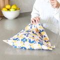 Person holding a floral-patterned reusable bag on a kitchen counter with lemons in the background.