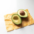 Half-cut avocado on a cracker with a white background