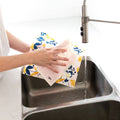 Person cleaning a kitchen sink with a floral dishcloth.
