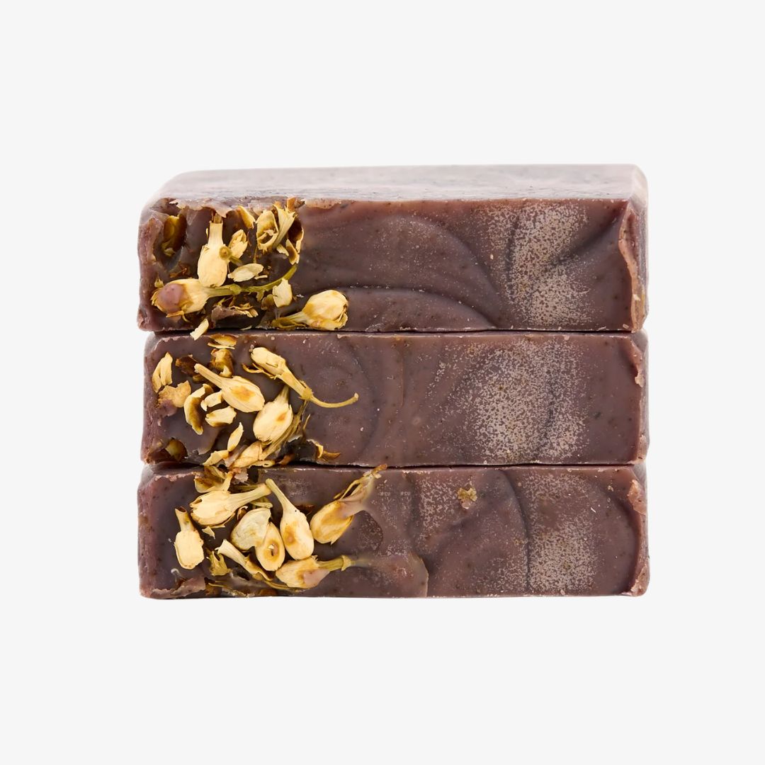 Three stacked soap bars with dried flowers on a white background