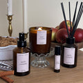 Candle and diffuser set with 'apple crumble' label on a wooden surface.