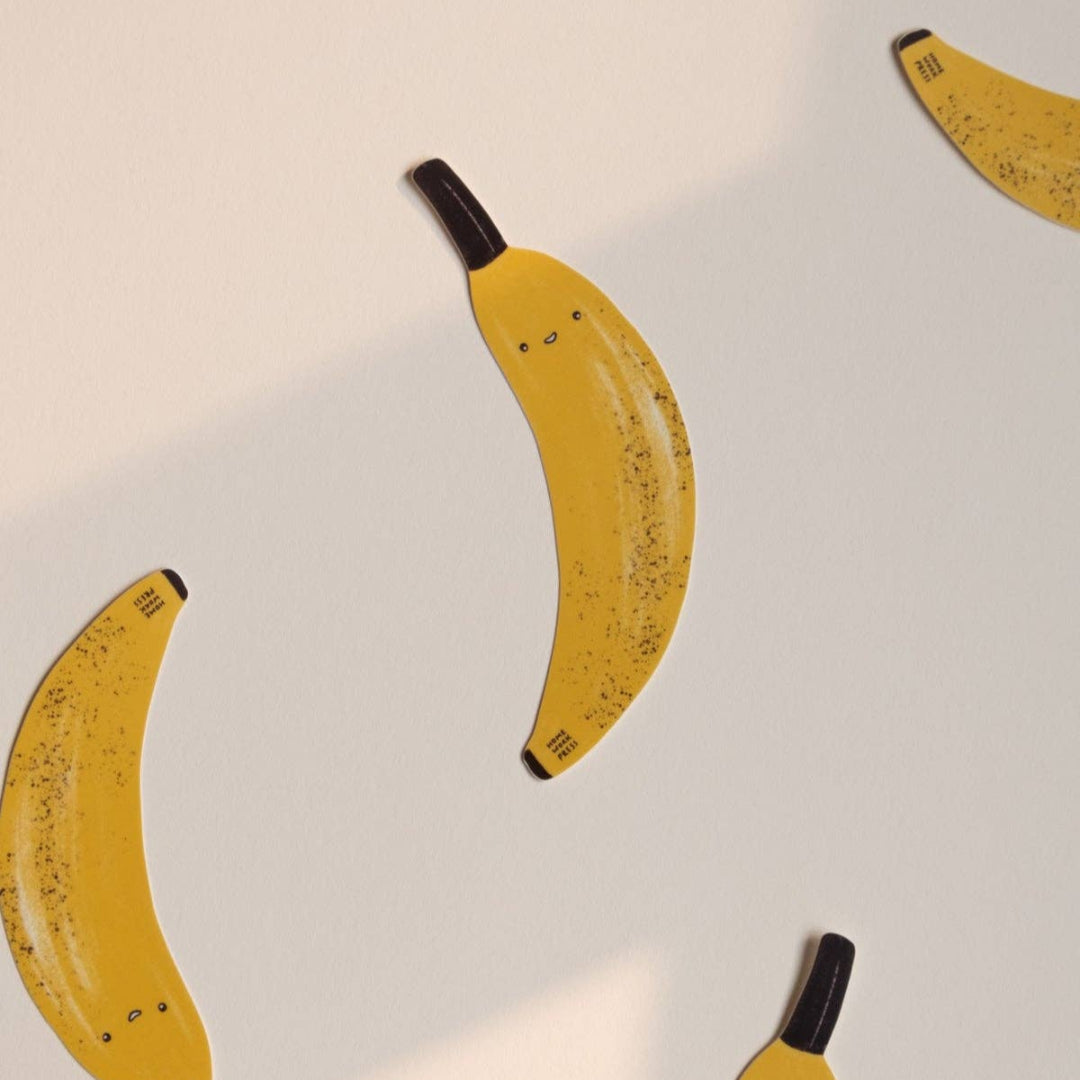 Yellow bananas with black stems on a light gray background