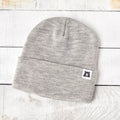 Gray beanie with a brand logo on a light wooden surface
