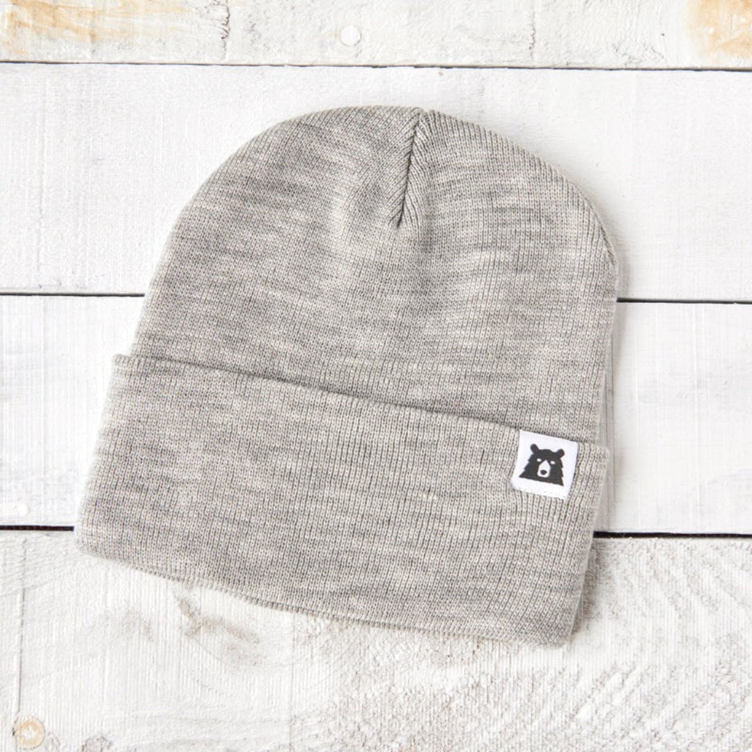 Gray beanie with a brand logo on a light wooden surface