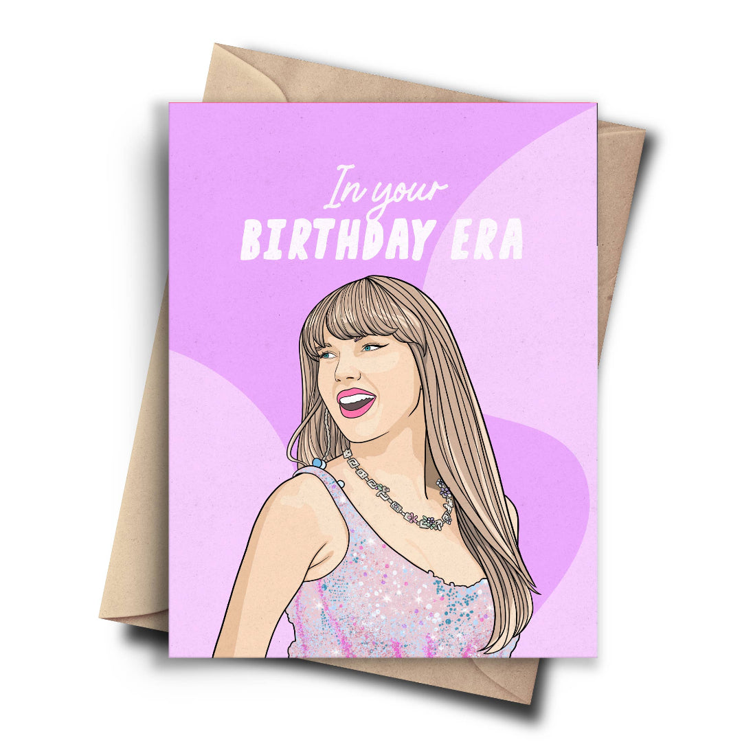 A humorous birthday card featuring a cartoon drawing of Taylor Swift in a pink, sequined bodysuit with her hair down. The text on the purple background reads, "In your BIRTHDAY ERA." A brown kraft envelope is behind the card.