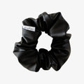Black scrunchie with a brand label on a white background
