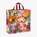 A reusable tote bag with a vibrant floral pattern. The bag features a variety of colorful flowers, including roses, lilies, and tulips, as well as a butterfly. The bag has dark red handles.