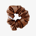Brown scrunchie with a brand label on a white background