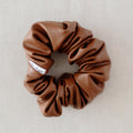 Brown scrunchie with a label on a light gray background