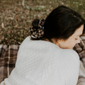 Person wearing a white sweater sitting on a plaid blanket outdoors