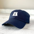 A navy blue baseball cap with a low profile and curved peak, featuring a cute white polar bear patch with black eyes and nose stitched on the front. Shop this at Cheerfully Made, Canadian-made gift shop.