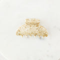 Gold hair clip on a white marble surface