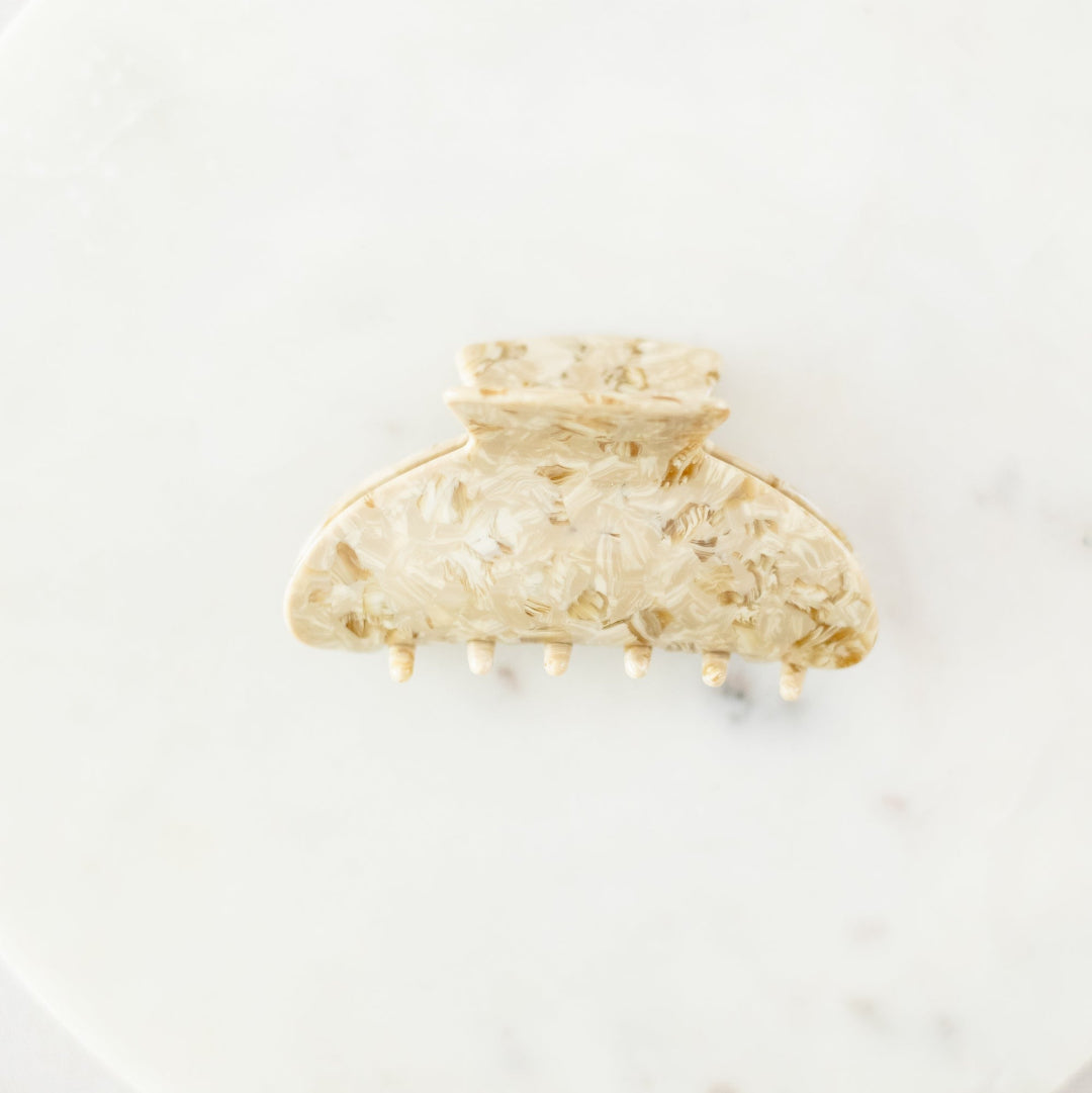 Gold hair clip on a white marble surface
