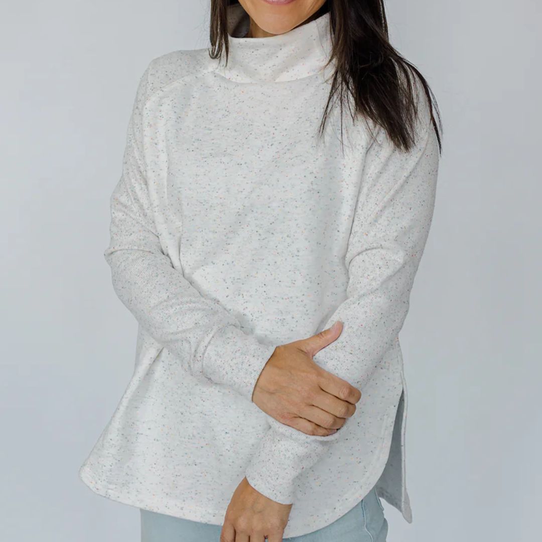 Person wearing a light gray turtleneck sweater against a plain background