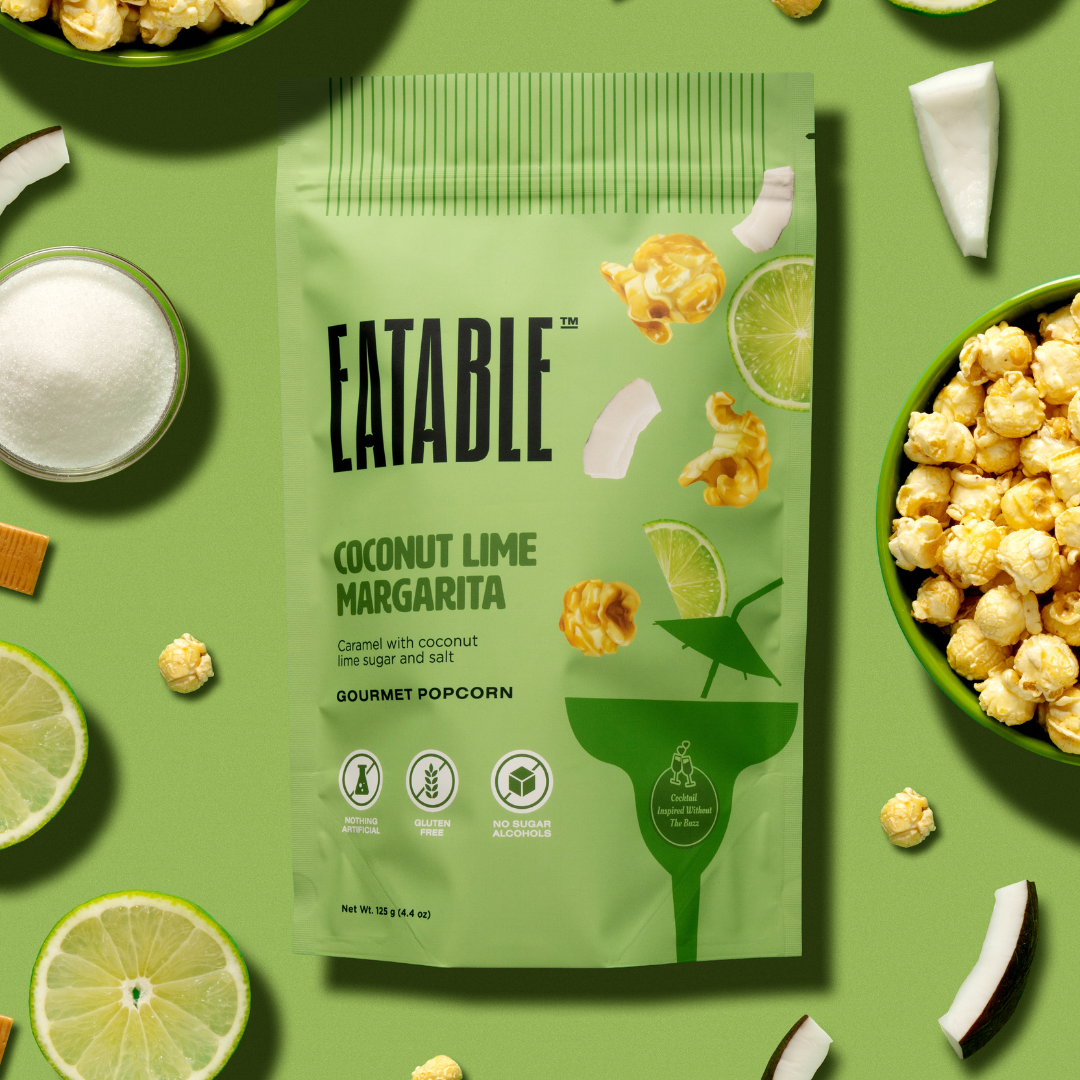 Eatable Coconut Lime Margarita popcorn package on a green background with popcorn and limes.