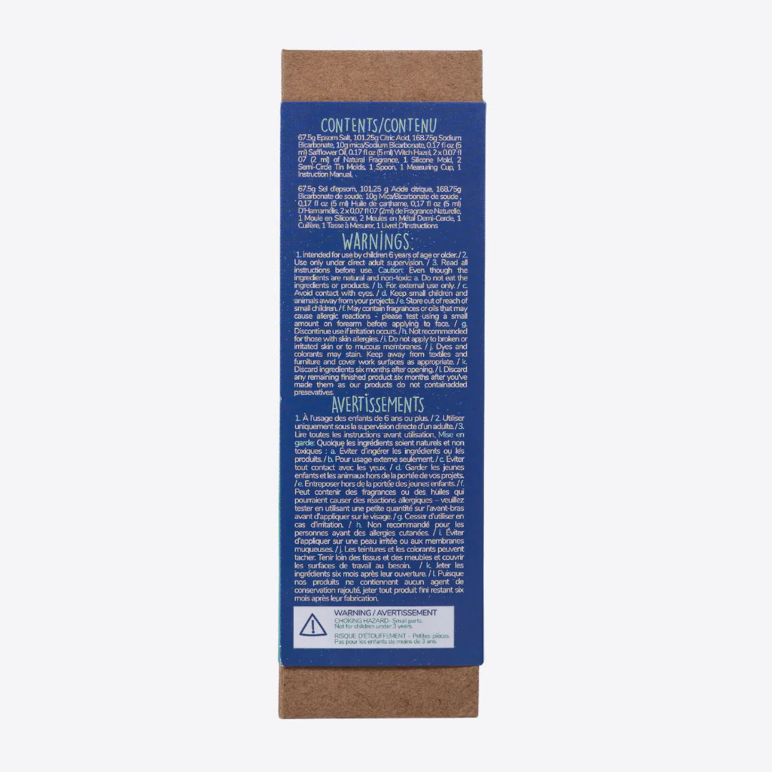 A cardboard box containing a Kiss Naturals Bath Bomb Kit. The box is green and white with the product name and a colorful illustration of bath bombs. It states that the kit is 100% natural, made in Canada, and suitable for ages 6 and up.