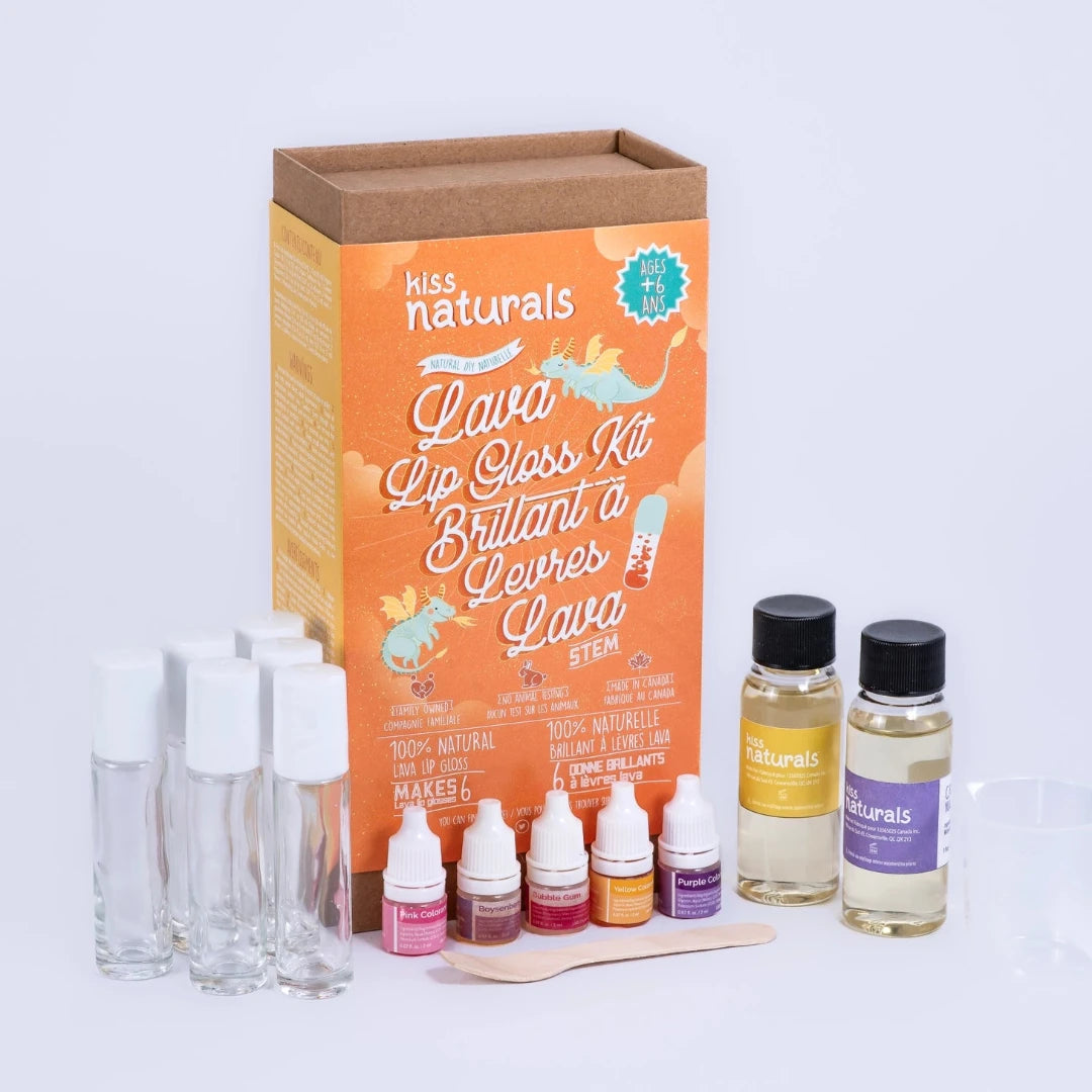 A cardboard box containing a Kiss Naturals Lava Lip Gloss Kit. The box is orange and white with the product name and a colorful illustration of a dragon. It states that the kit is 100% natural, made in Canada, and suitable for ages 6 and up.