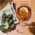 Glass of iced tea with lemon slices and garnishes on a tiled surface