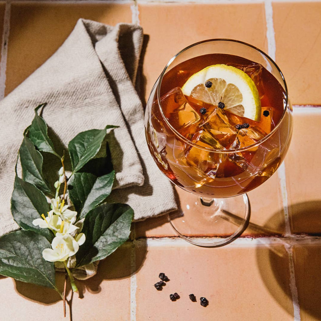 Glass of iced tea with lemon slices and garnishes on a tiled surface