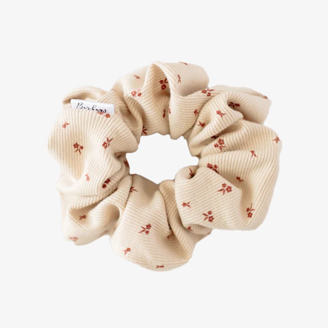 Beige scrunchie with small red floral patterns on a white background