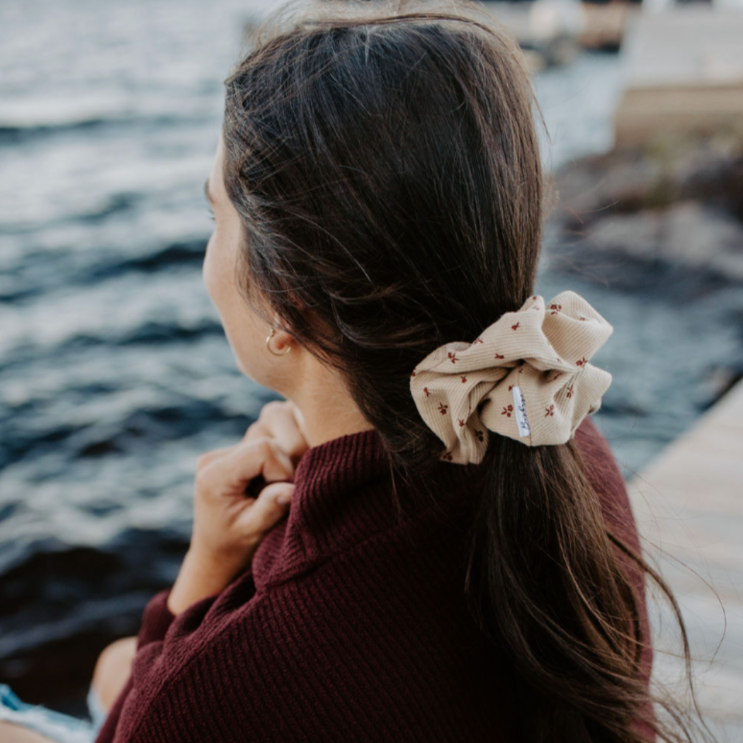 Woman sitting by a body of water with a scrunchie in her hair