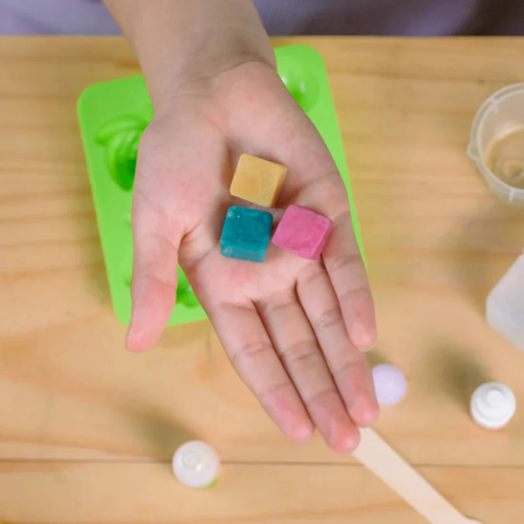 A cardboard box containing a Kiss Naturals Glycerin Soap Kit. The box is blue and white with the product name and a colorful illustration of penguins. It states that the kit is 100% natural, made in Canada, and suitable for ages 6 and up.