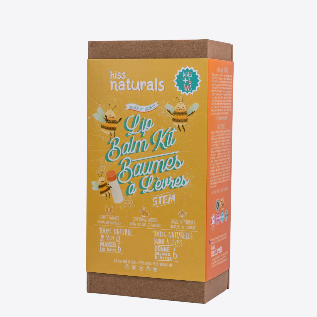 A cardboard box containing a Kiss Naturals Lip Balm Kit. The box is yellow and white with the product name and a colorful illustration of bees. It states that the kit is 100% natural, made in Canada, and suitable for ages 6 and up.