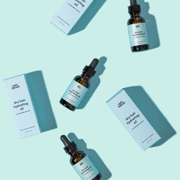 A small, amber glass dropper bottle of Epic Blend dry hair hydrating oil, featuring a light blue label with product details.