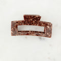 Brown marble hair clip on a white marble surface