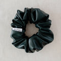 Dark green scrunchie with a brand label on a light gray background