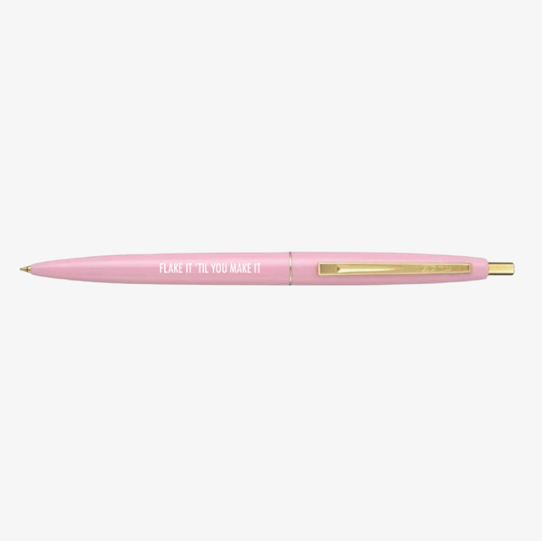 A light pink ballpoint pen with a gold clip. The barrel of the pen is inscribed with "FLAKE IT 'TIL YOU MAKE IT" in white capital letters.