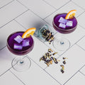 Two purple cocktails with orange slices on a tiled surface