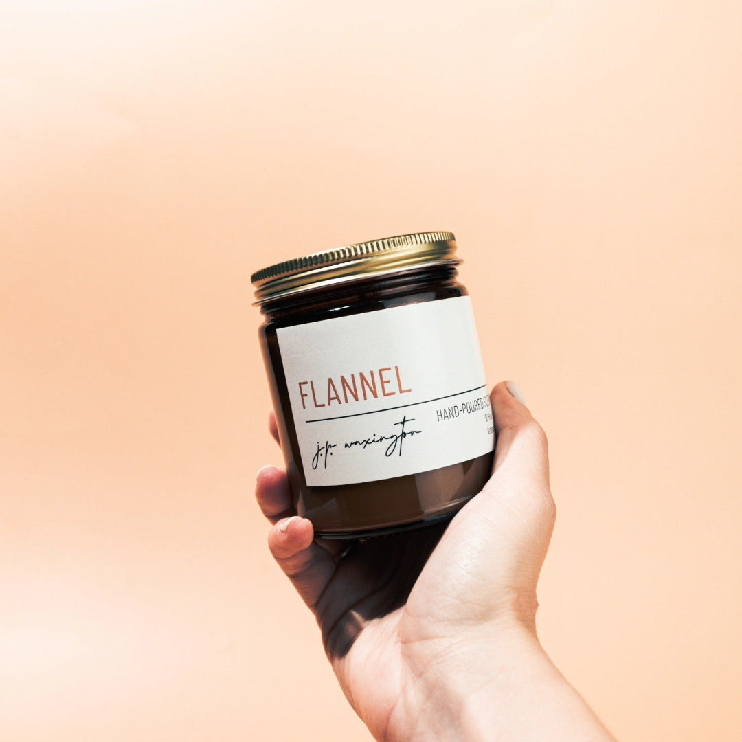 Hand holding a jar labeled 'Flannel' against a peach background