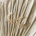 Gold hoop earrings on a textured beige surface