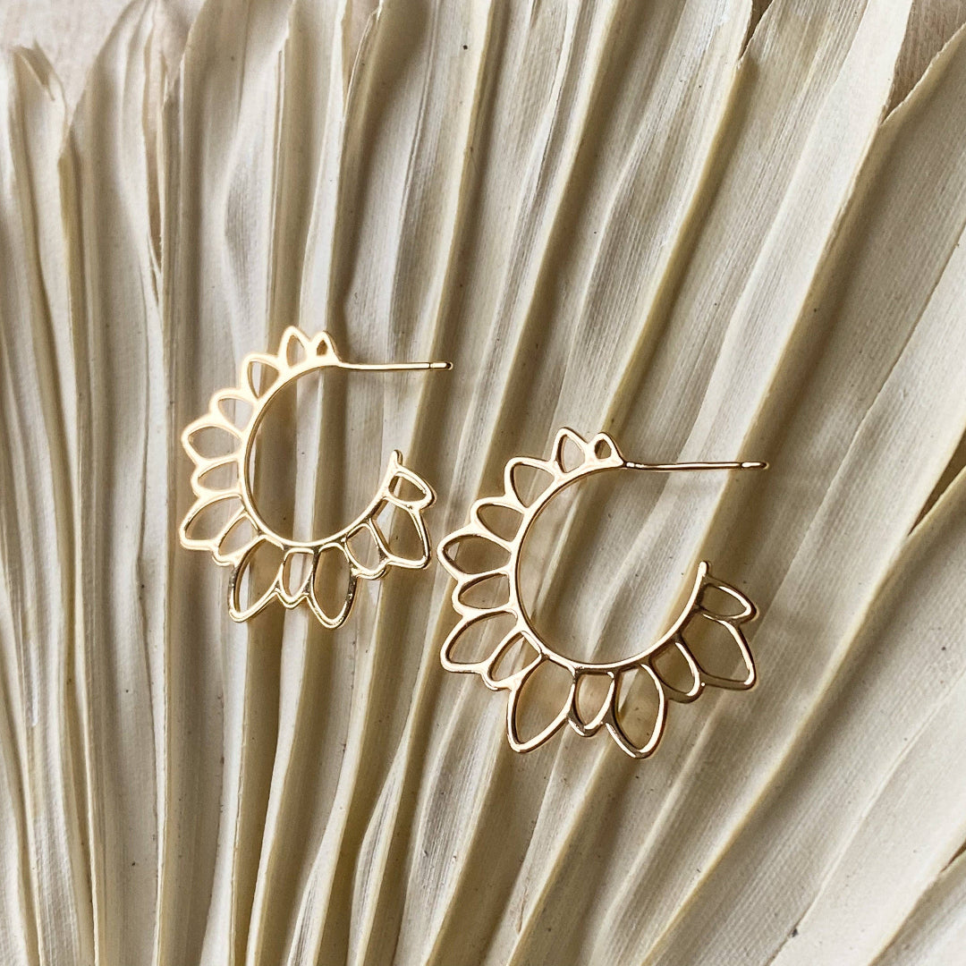 Gold hoop earrings on a textured beige surface