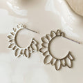 Silver hoop earrings on a white ceramic dish