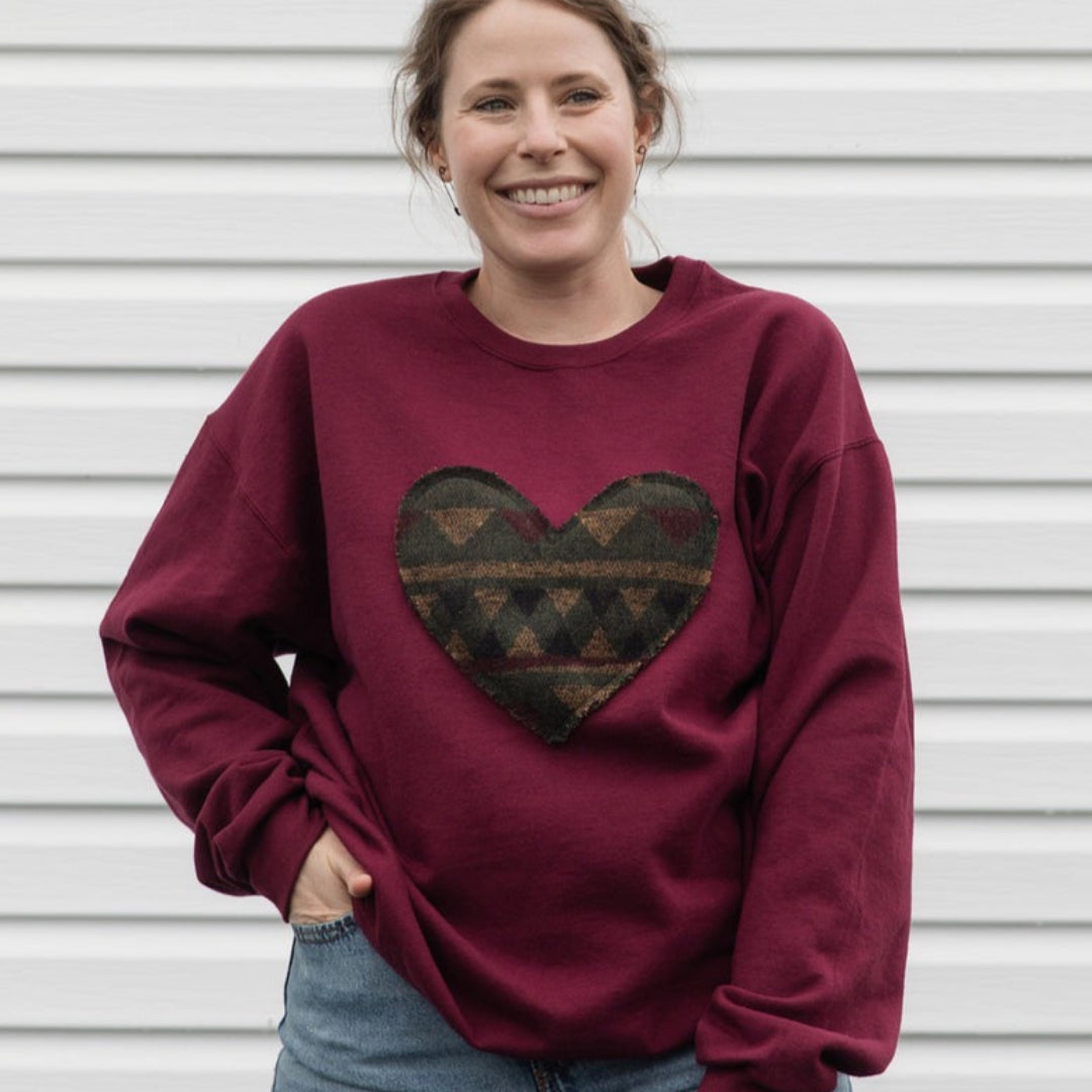 Woman wearing a burgundy sweatshirt with a heart design against a white background