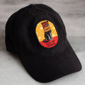 Black cap with a colorful patch featuring a dog and text on a gray surface