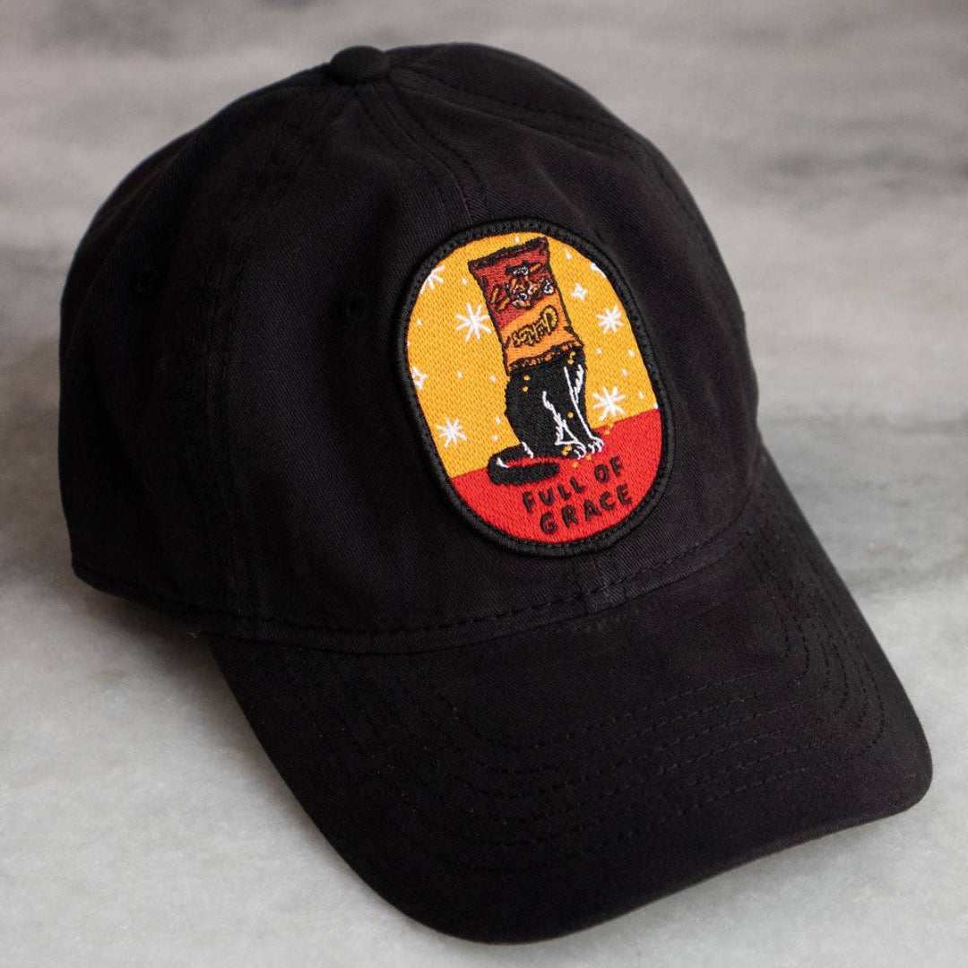 Black cap with a colorful patch featuring a dog and text on a gray surface