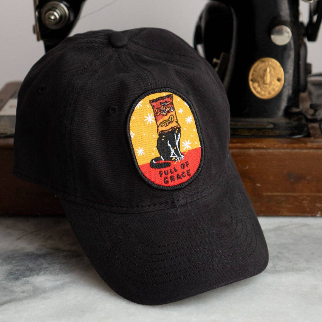 Black cap with a patch in front of an old Singer sewing machine.