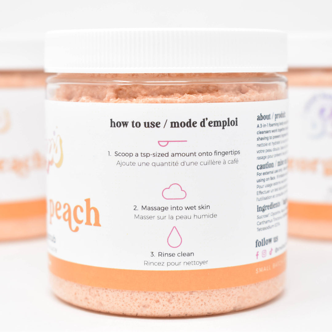 Jar of peach-scented body scrub with label on a white background
