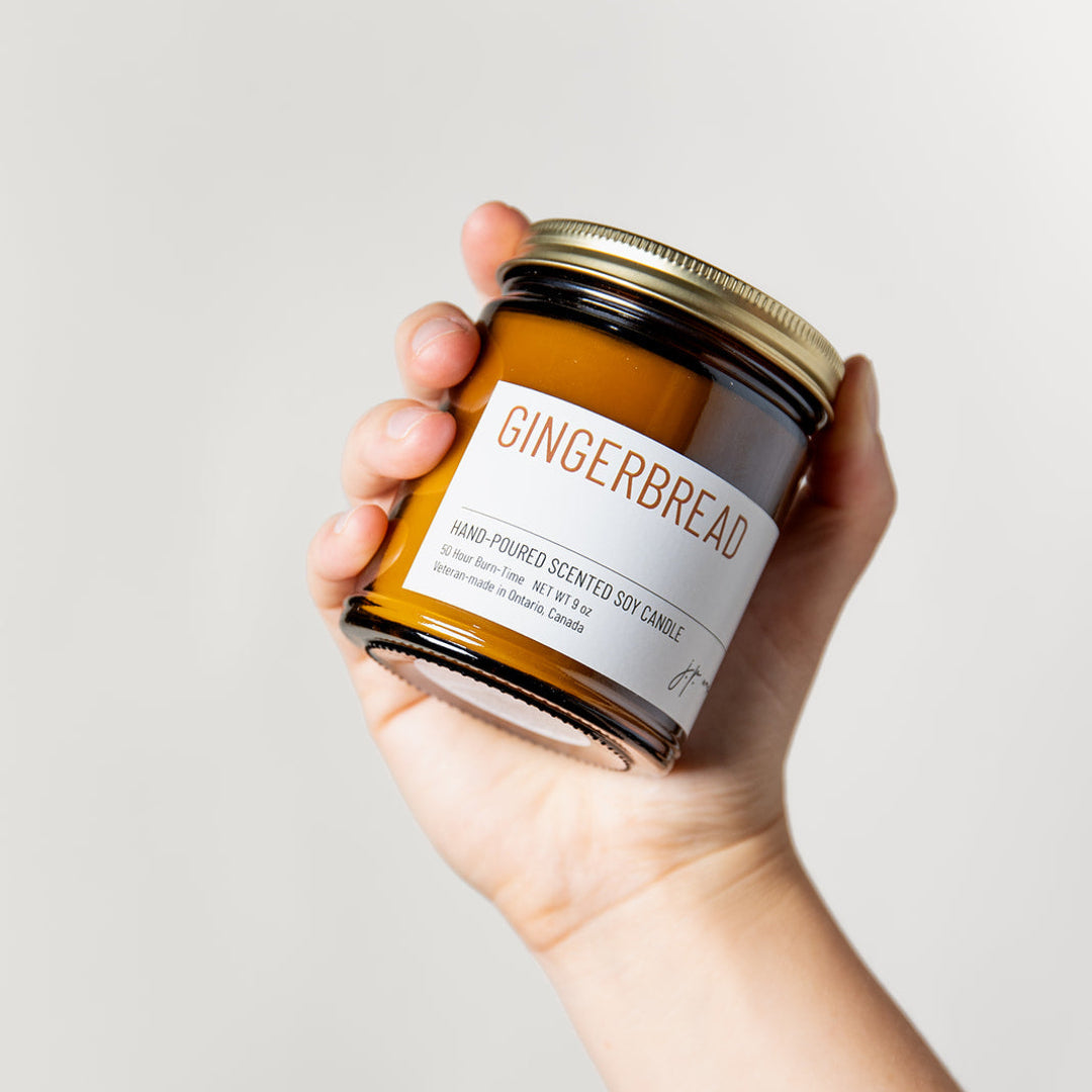 Hand holding a jar of gingerbread-flavored product against a plain background