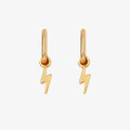 A pair of gold earrings with lightning bolt charms on a pink background. The earrings are displayed on a card with the brand name "Foxy Originals."