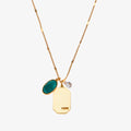 A gold necklace with an emerald stone pendant. The pendant also has the word "HOPE" engraved on it. The necklace is displayed on a green card with the month "May" and the brand name "Foxy Originals."