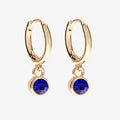 A set of three pairs of sapphire earrings displayed on a blue card. The set includes a pair of stud earrings, a pair of bar earrings with small sapphire beads, and a pair of hoop earrings with dangling sapphire stones. The card has the month "September" and the brand name "Foxy Originals."