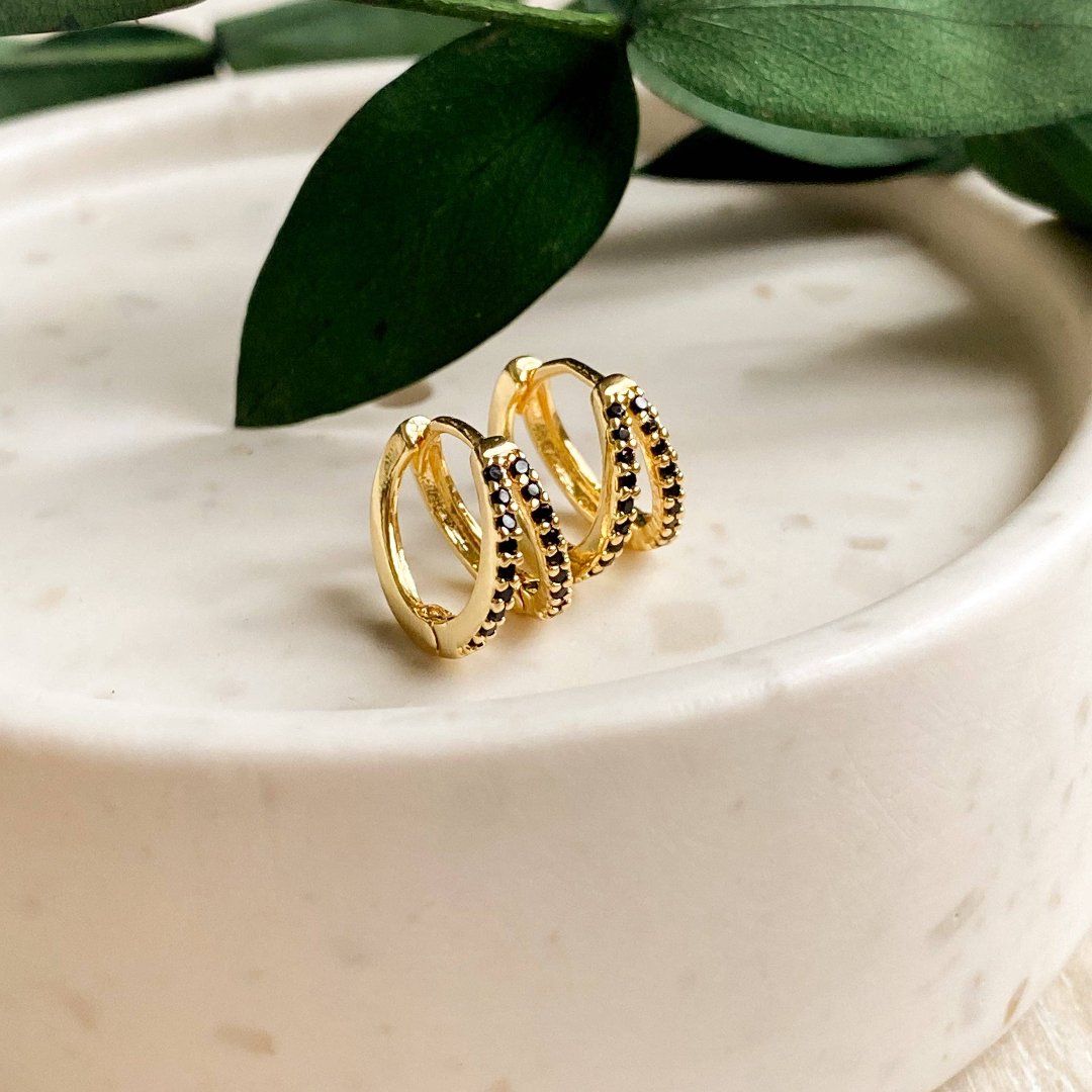 A pair of gold hoop earrings with black beading.