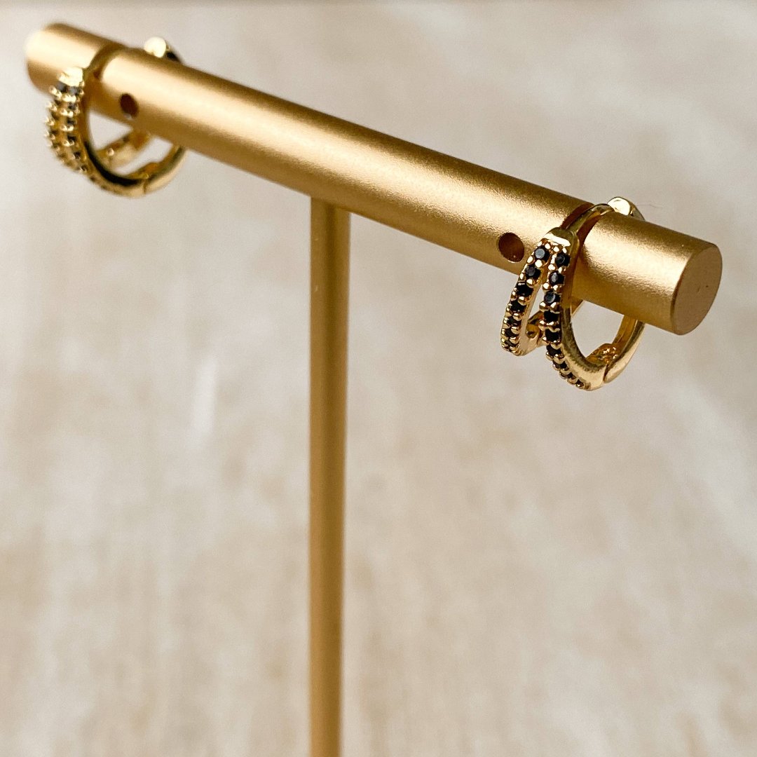 A pair of gold hoop earrings with black beading.